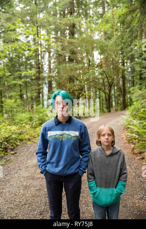 Portrait von Geschwister stehen auf der Straße inmitten von Bäumen in Olympic National Park Stockfoto