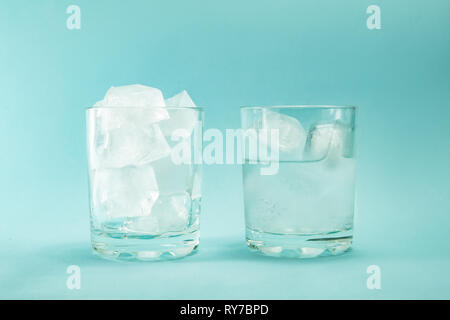 Сoncept der globalen Erwärmung. Schmelzen von Eis in einem Glas auf einem blauen Hintergrund. Stockfoto