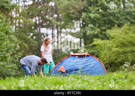 Paar ist Camping und Zelten auf einer Wiese in der Natur im Sommerurlaub Stockfoto