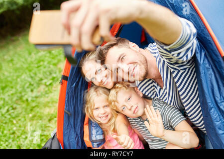Familie mit Kindern im Zelt ist ein selfie mit Smartphone beim Camping Stockfoto