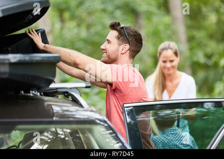 Man verstaut das Gepäck im Dach, im Auto vor der Fahrt in den Urlaub Stockfoto