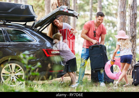 Kinder Eltern helfen, das Gepäck zum Auto tragen, bevor Sie auf Geschäftsreise Stockfoto