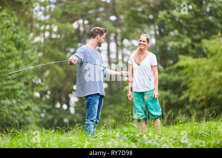 Junges Paar in einer Wiese baut das Camping Zelt zusammen mit zeltstangen Stockfoto