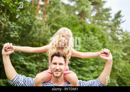 Vater trägt seine glückliche Tochter auf den Schultern Huckepack in der Natur Stockfoto