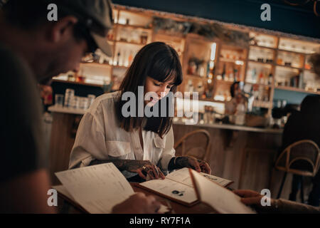 Freunde lesen Getränke Menüs in einer Bar in der Nacht Stockfoto