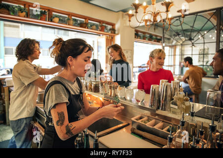 Junge weibliche Barkeeper gießen Cocktails hinter einer Theke Stockfoto