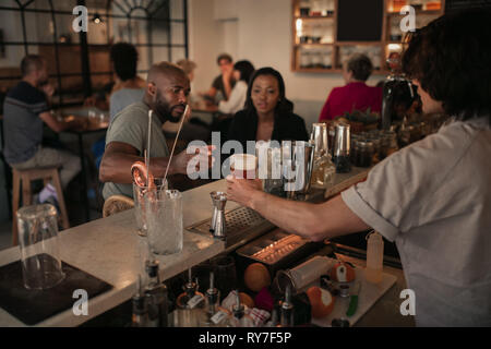 Junges Paar Drinks in der Bar am Abend Stockfoto