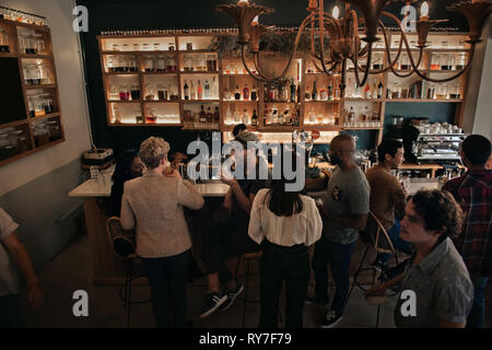 Unterschiedliche Menschen, um einen Drink in einem Pub am Abend Stockfoto