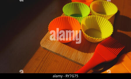 Silikon Pinsel und Cupcake Büchsen auf hölzernen Tisch. Küche und kochen Konzept auf hölzernen Hintergrund Stockfoto