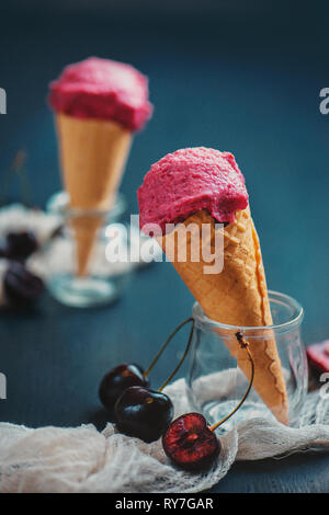 Rosa Eis in Waffeln mit Kirschen. Dunkle essen Fotografie mit Kopie spacee Stockfoto