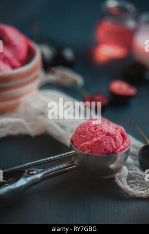 Hausgemachte rosa Eis in Eis Löffel mit Kirschen und Pflaumen. Dunkle essen Fotografie mit Kopie Raum Stockfoto