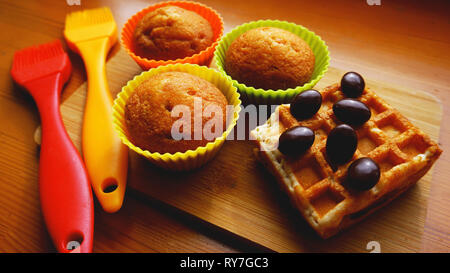 Einfachen mini Muffins in bunten Silikon Backformen und Waffeln. Küche und kochen Konzept auf hölzernen Hintergrund Stockfoto