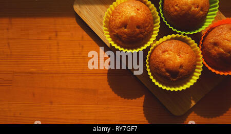 Einfachen mini Muffins in bunten Silikon Backformen. Freien Speicherplatz. Nahaufnahme. Küche und kochen Konzept auf hölzernen Hintergrund Stockfoto