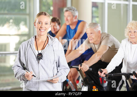 Frau mit Stoppuhr und Schulungsplan als Trainer für Senioren im Fitnesscenter Stockfoto