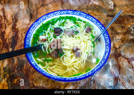 Chinesische Nudeln Suppe mit Stäbchen und Rindfleisch Chunks in eine Schüssel geben. Stockfoto
