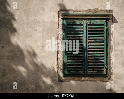 Alte verwitterte und abgenutzte grünen Fensterläden, die eine Seitenstraße Fenster an einem sonnigen Tag, Dubrovnik, Kroatien Stockfoto