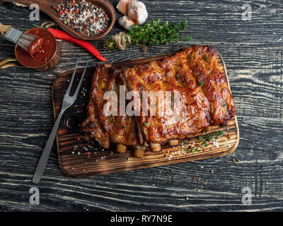 Gegrillte Schweinerippchen mit Sauce auf einem Schneidebrett, Gewürze, Marinade Stockfoto
