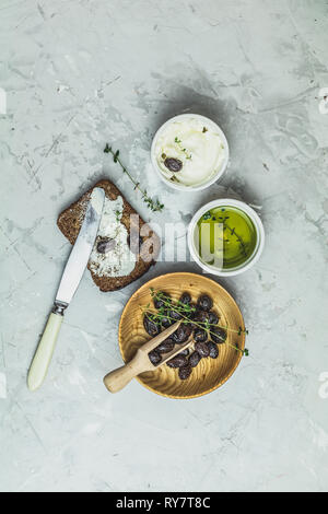 Vollkornbrot gebacken zu Hause, bio Zutaten, sehr gesund mit Saatgut, Schüssel mit Frischkäse und traditionelle griechische italienische Vorspeisen getrocknete Oliven auf Stockfoto