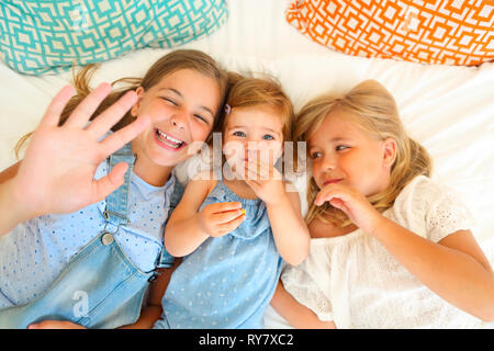 Portrait der drei glücklichen kleinen Schwestern auf einem Bett Spaß Stockfoto