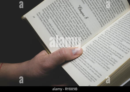 Herren Hand hält er ein offenes Buch bereit zum Lesen. Nahaufnahme Stockfoto