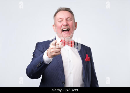 Reifer Mann im blauen Anzug Zeigefinger und toothy Lächeln. Studio shot Stockfoto