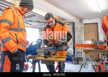 Forstwirtschaft Skills: Menschen, die in einem eintägigen Workshop in, wie man die Schneiden auf die Links einer Kettensäge schärfen, und für die Betreuung sicher und die Power Tool verwenden. Wales UK Stockfoto