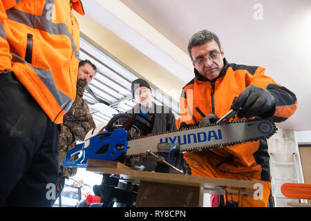 Forstwirtschaft Skills: Menschen, die in einem eintägigen Workshop in, wie man die Schneiden auf die Links einer Kettensäge schärfen, und für die Betreuung sicher und die Power Tool verwenden. Wales UK Stockfoto