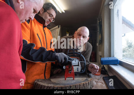 Forstwirtschaft Skills: Menschen, die in einem eintägigen Workshop in, wie man die Schneiden auf die Links einer Kettensäge schärfen, und für die Betreuung sicher und die Power Tool verwenden. Wales UK Stockfoto