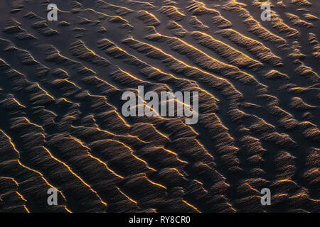 Sand Wellen Texturen und Pfützen auf Strand Küste bei Sonnenuntergang Stockfoto