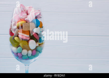 Wein Glas mit Süßigkeiten in verschiedenen Farben gefüllt. Stockfoto