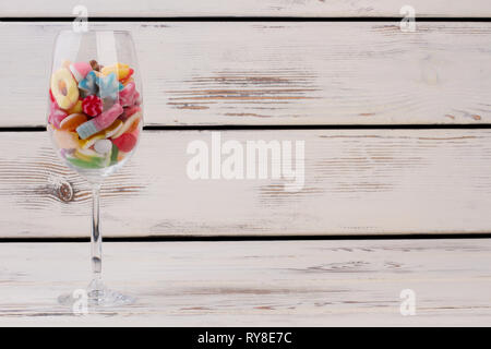 Wein Glas mit verschiedenfarbigen Bonbons gefüllt. Stockfoto