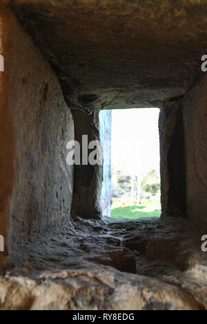 Blick durch ein kleines Fenster in einer alten Steinmauer Stockfoto
