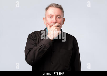 Älterer Mann im schwarzen T-Shirt denken über seine Probleme. Stockfoto