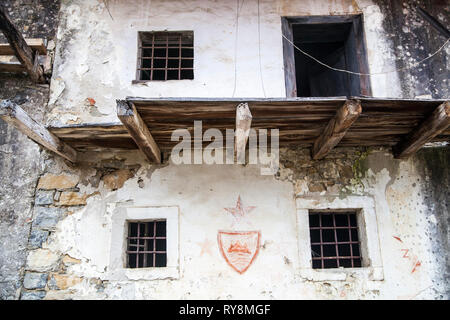 Fassade mit gebrochenen Balkon, drei rote Sterne und ein rotes Wappen Sloweniens. Das Haus befindet sich in einem verlassenen Dorf Slapnik in der Region Goriška Brda, Stockfoto