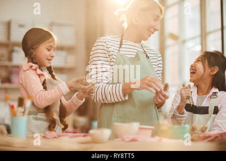 Taille bis Portrait von Kunst Lehrer die Arbeit mit Kindern in der Keramik Klasse, Szene beleuchtet, die durch Sonnenlicht Stockfoto