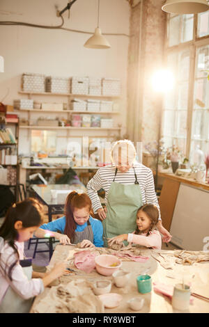 Hohen winkel Porträt der weiblichen Kunst Lehrer, die mit Kindern arbeiten in der Keramik Klasse, Szene beleuchtet durch heitere Sonnenlicht, Kopie Raum Stockfoto