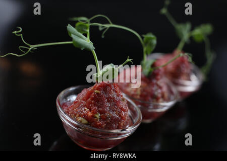 Rote schmackhafte Sauce Tartar in drei pialas, mit einem Schaft der Gekeimten grüne Erbsen eingerichtet, Nahaufnahme, für ein Menü Stockfoto
