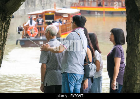 Chinesische Touristen Familie selfie Stick Bilder mit Großeltern - Clarke Quay, Singapur Stockfoto