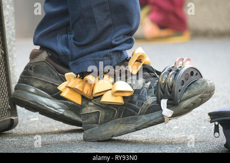 Kastagnetten und Tamburin Closeup auf Tennis Schuhe, von "One Man Band" Interpret auf der Orchard Road - Singapur Stockfoto