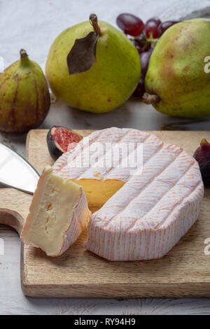 Rundes Stück französischer Käse Fleur Rouge aus Kuhmilch hergestellt als Dessert serviert mit frischen Feigen und Birnen Nahaufnahme Stockfoto