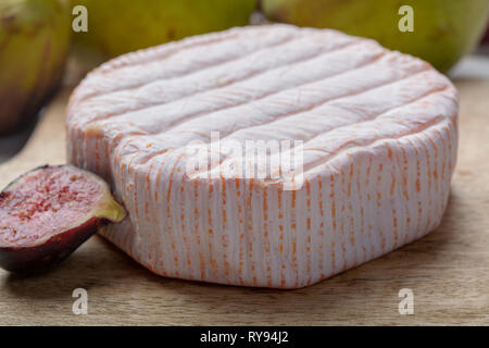 Rundes Stück französischer Käse Fleur Rouge aus Kuhmilch hergestellt als Dessert serviert mit frischen Feigen und Birnen Nahaufnahme Stockfoto