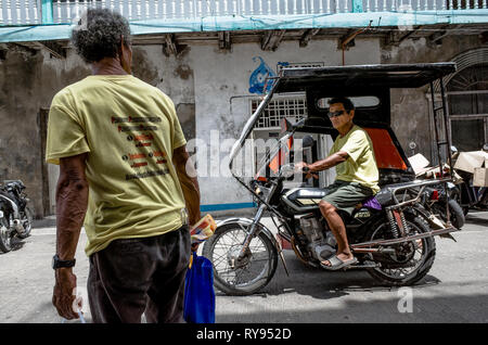 Eine ältere Filipino mann Uhren ein Dreirad driver vorbei auf die Straße - romblon City, Philippinen Stockfoto