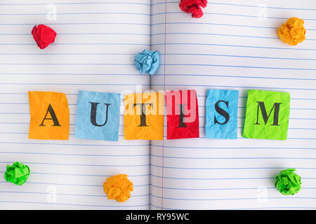 Autismus. Wort Autismus auf Notebook Blatt mit einigen bunten zerknittertes Papier Kugeln um ihn herum. Close Up. Stockfoto