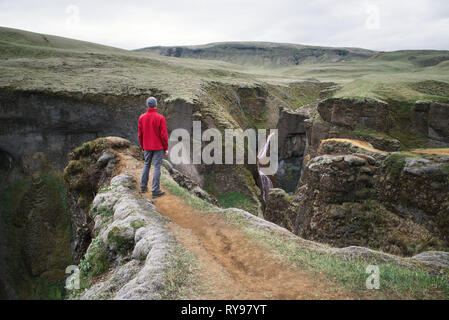 Fjadrargljufur Canyon Es ist in der Nähe des Ring Road, nicht weit von dem Dorf Kirkjubaejarklaustur. Touristen in der roten Jacke steht auf einem Hügel. Touri Stockfoto