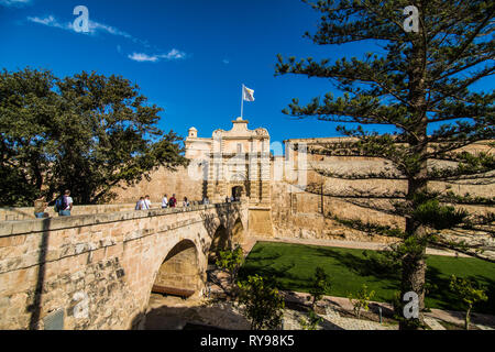 MDINA, MALTA - November, 2018 - Touristen überqueren Sie die Fußgängerbrücke zum Stadttor und Stadtzentrum, Mdina, Malta, Stockfoto