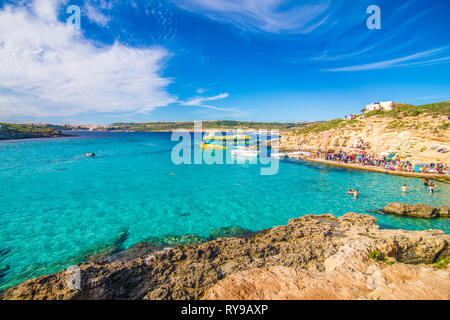 Comino, Malta - November, 2018: Touristen Masse an der Blauen Lagune das klare, türkisfarbene Wasser an einem sonnigen Sommertag mit klarem, blauem Himmel und Boote zu genießen Stockfoto