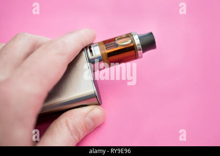 Hand mit vape pen Metall elektronische Zigarette vaping rosa Hintergrund Stockfoto