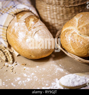 Platz Foto von zwei verschiedenen Arten von frisch gebackenem Brot auf einem urigen Hintergrund mit Weizen und Mehl. Eine Bäckerei und ein Lebensmittelgeschäft. Stockfoto