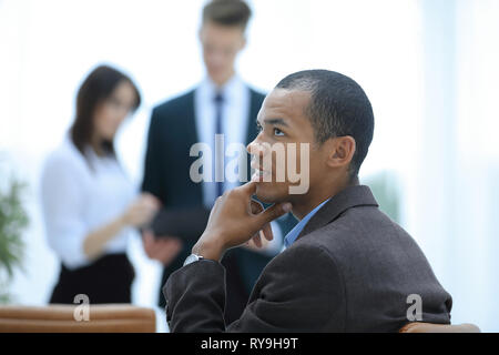 Junge erfolgreiche Geschäftsmann auf Hintergrund von Office Stockfoto