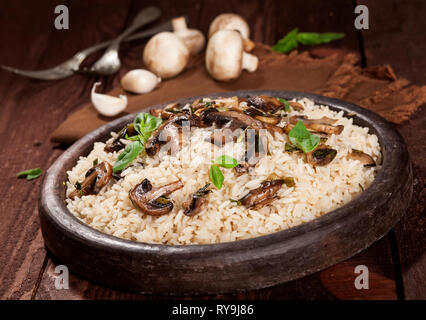 Weißer Reis mit Champignons in eine Schüssel auf hölzernen Hintergrund gekocht. Stockfoto